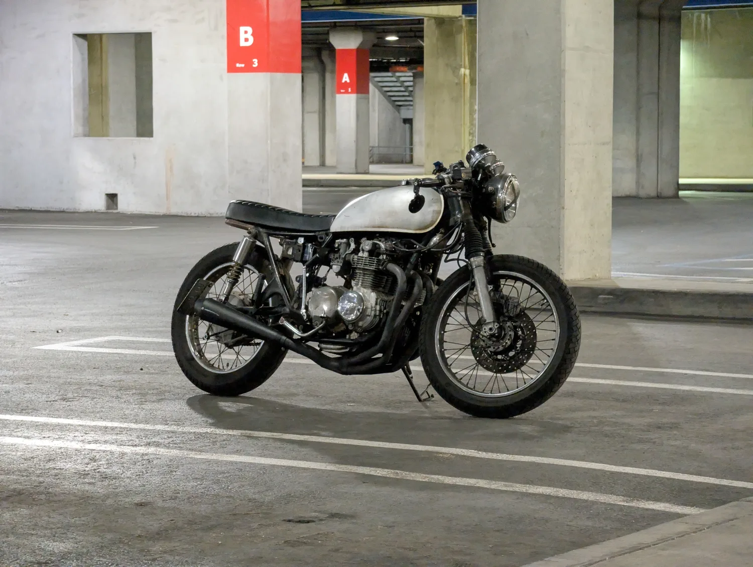 Brat style cafe racer built from a CB550, in a parking garage